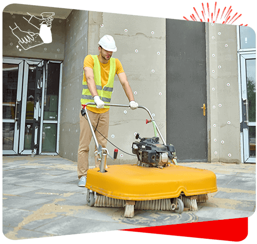 Industrial cleaning worker operating floor scrubber outside building.
